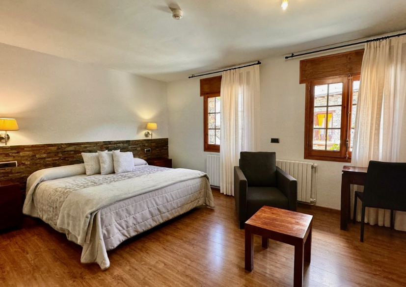 Habitació amb llit doble, tauleta i dues butaques